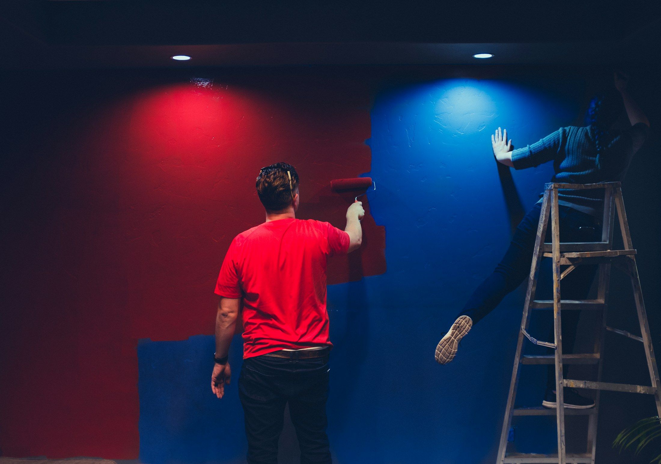 Pintores a aplicar vermelho e azul numa parede interior