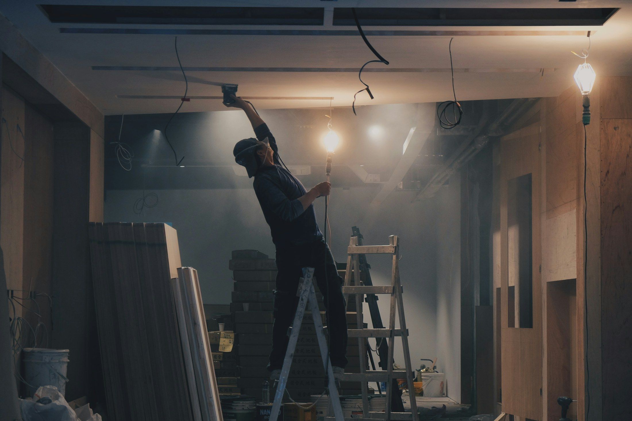 Profissional num escadote a trabalhar no tecto de uma obra